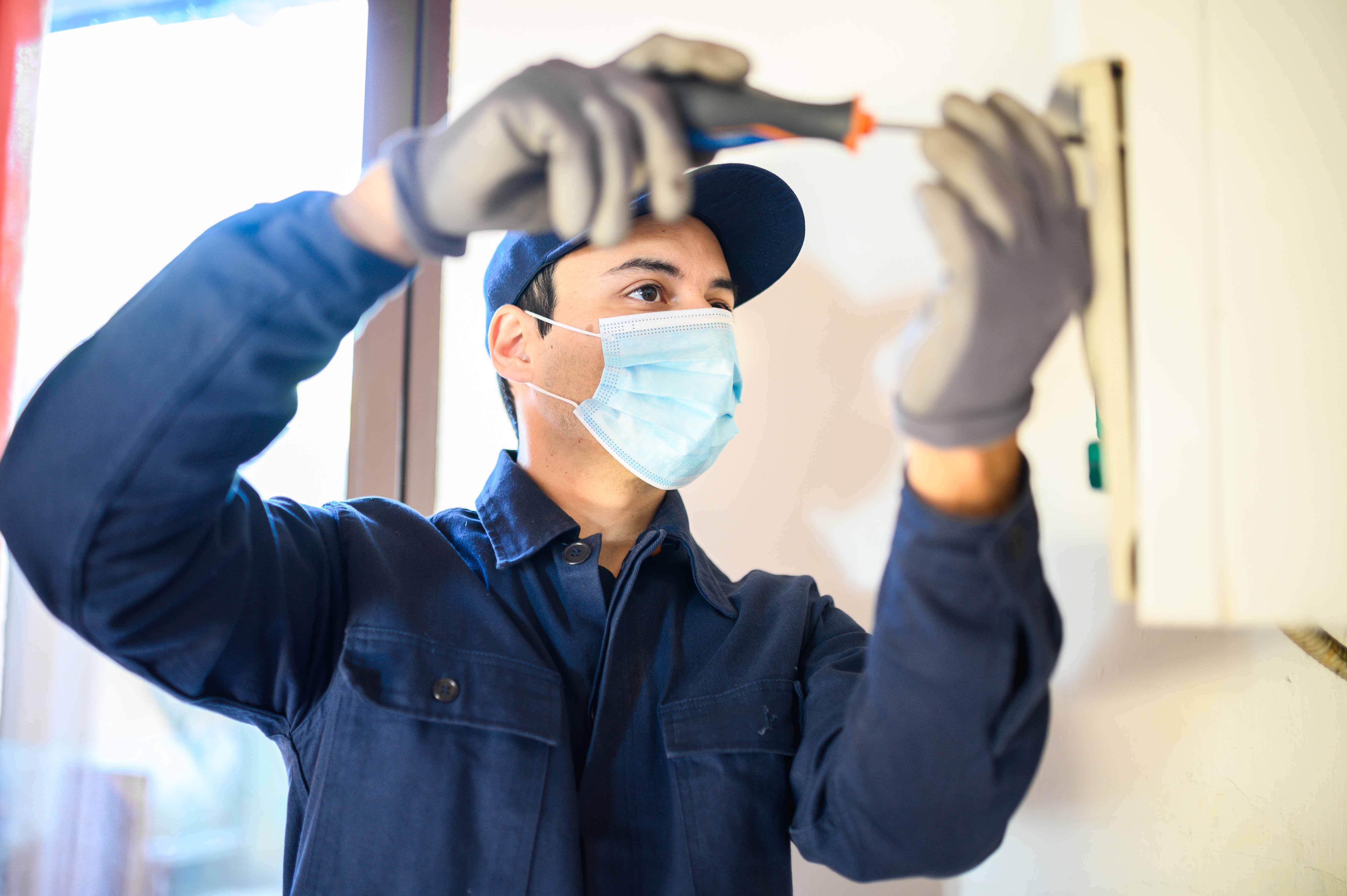 smiling-technician-repairing-hot-water-heater-wearing-mask-due-coronavirus-pandemic